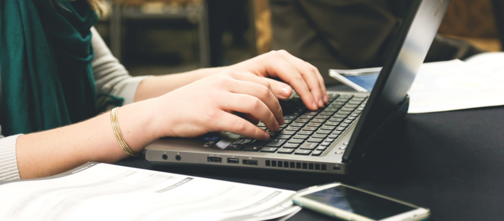 foto van een vrouw die een tekst op haar laptop schrijft